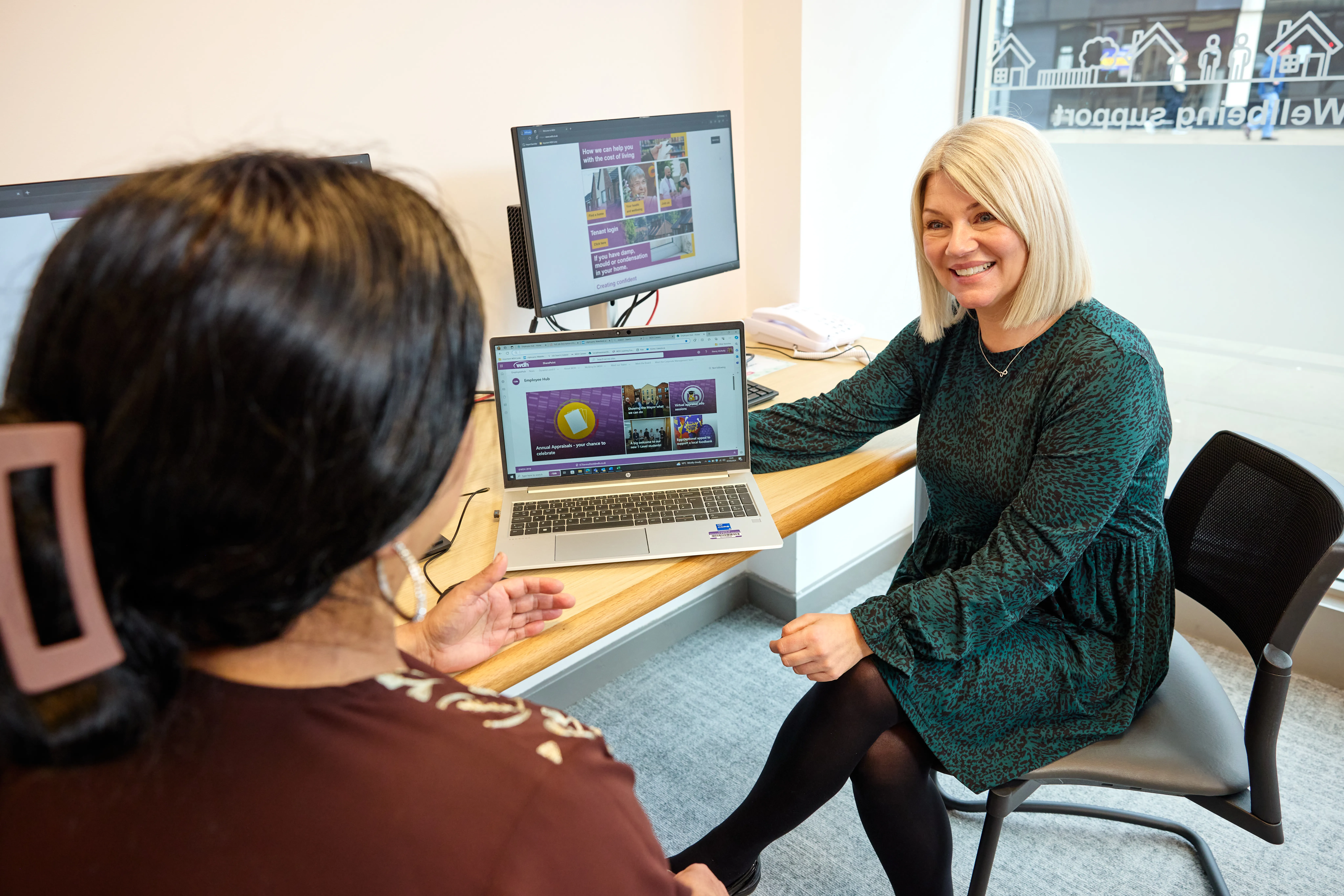 Community Employment Advisor sat down speaking to a customer in front of a laptop. 