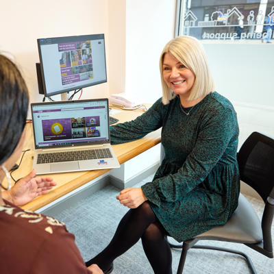 Community Employment Advisor sat down speaking to a customer in front of a laptop.